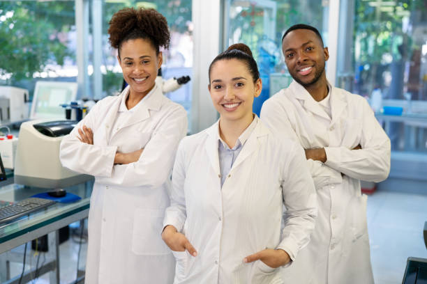 Portrait of a three scientists standing together in laboratory. Multiracial male and female doctors wearing lab coat looking at camera and smiling.